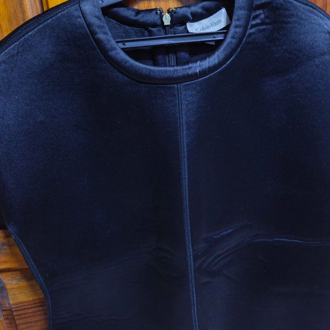 Calvin Klein Black Short Sleeve Top (Category: Shirts) located in Baguio. Submitted by jbv.ph (Listing ID 1465573608, Image 2). Description: - Brand: Calvin Klein - Color: Classic Black - Material: Premium structured fabric - Design: Short sleeves, rounded neckline, and flattering front/back seam details - Closure: Exposed back zipper with branded gold pull tab - Style: Clean, minimal, and versatile (great for work or going out) - Condition: Exce