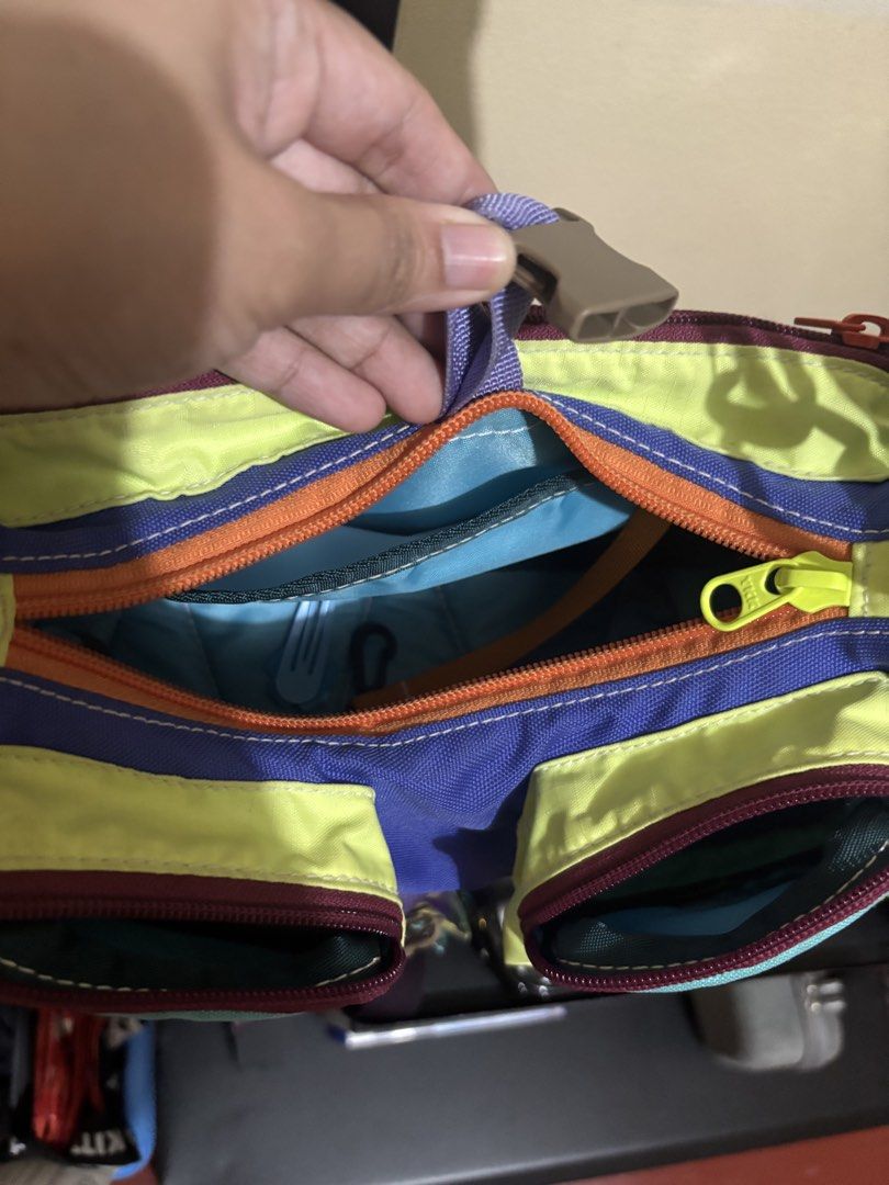 Carryom Gopi (Category: Shoulder Bags) located in Muntinlupa City. Submitted by ashley.18 (Listing ID 1465488465, Image 3). Description: - Vibrant color-block design mixing purple, teal, lime green, and orange - Main zip compartment with internal slip pockets for easy organization - Two convenient front zippered pockets and a plastic buckle flap closure - Thick teal fabric strap with adjustable knotted sections and metal swivel clasps - Structure