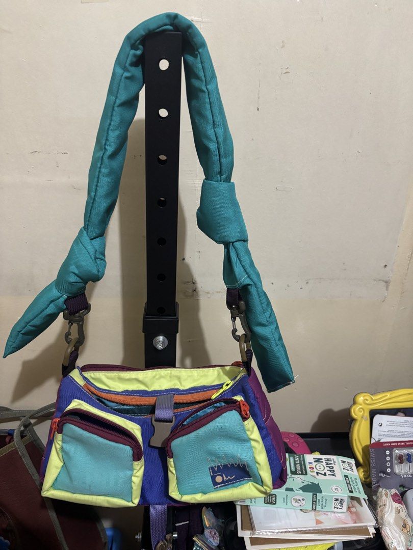 Carryom Gopi (Category: Shoulder Bags) located in Muntinlupa City. Submitted by ashley.18 (Listing ID 1465488465, Image 1). Description: - Vibrant color-block design mixing purple, teal, lime green, and orange - Main zip compartment with internal slip pockets for easy organization - Two convenient front zippered pockets and a plastic buckle flap closure - Thick teal fabric strap with adjustable knotted sections and metal swivel clasps - Structure