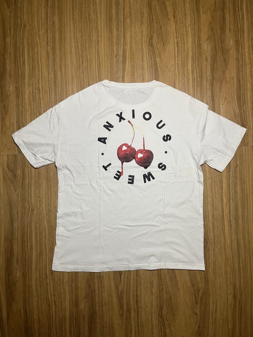 Cider Sweet But Anxious Cherry M•20x25 (Category: Shirts) located in Cebu City. Submitted by guttathreads (Listing ID 1465429803, Image 2). Description: - Brand: Cider - Style: Sweet But Anxious Cherry Graphic Tee - Size: M (Width: 20", Length: 25") - Color: White - Design: Minimalist 'Sweet But Anxious' text on the front; striking heart-cherry graphic with circular text on the back - Condition: 7/10, well-maintained and comfortable cotton fabric