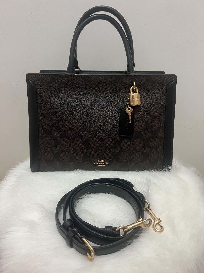 Coach Signature Bag with Lock and Strap (Category: Cross-body Bags) located in Paoay. Submitted by rvf1230 (Listing ID 1465390491, Image 3). Description: - Authentic Coach tote bag in dark brown signature monogram canvas - Features sleek black leather trim and polished gold-tone hardware - Includes charming hanging padlock and key accents - Comes with a detachable black leather shoulder strap and top handles - Convenient open slip pocket on the b
