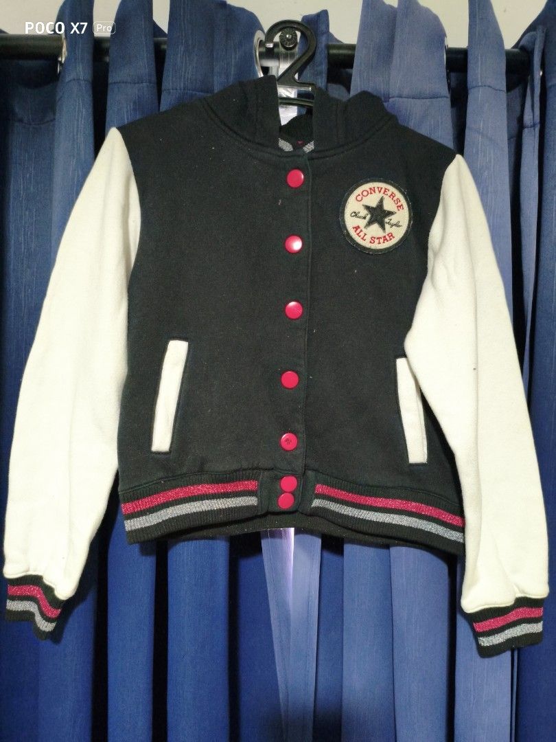 Converse All Star Varsity Bomber Jacket Black White (Category: Babies & Kids Fashion) located in Cainta. Submitted by sjprelovedbotique (Listing ID 1465413628, Image 1). Description: - Brand: Converse All Star - Style: Varsity jacket with warm hood - Color: Black body with white sleeves - Details: Bright pink snap buttons, dual side pockets - Accents: Striped ribbed cuffs and hem with sparkly thread - Logo: Classic Chuck Taylor All Star circular 