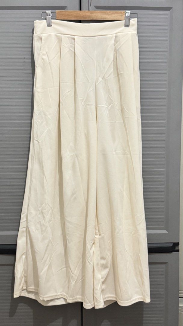 Cream Wide Leg Pleated Pants (Category: Other Bottoms) located in Quezon City. Submitted by heyhaveaniceday (Listing ID 1465504714, Image 1). Description: - Color: Cream - Style: Wide leg pants with front pleats - Features: Functional side pockets and comfortable back elastic waistband - Material: Flowy fabric with a nice drape - Versatility: Easy to pair with basic tops or blouses for work or casual wear.