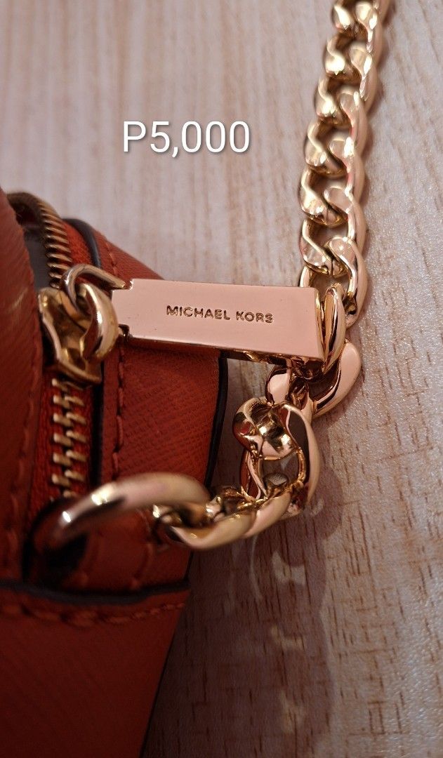 Cross Body Sling Bag (Category: Cross-body Bags) located in Paranaque City. Submitted by tubby.kat (Listing ID 1465574994, Image 3). Description: This is a Michael Kors Jet Set Large Saffiano Leather Crossbody Bag (often referred to as an East West camera bag) in a vibrant orange/burnt sienna hue. Key Features & Design • Material: Crafted from durable, scratch-resistant Saffiano leather which gives it a distinct cross-hatch texture and a structur
