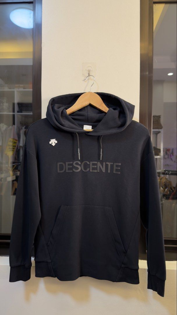 Descente Black Pullover Hoodie Size M (Category: Coats, Jackets and Outerwear) located in Paranaque City. Submitted by preluxeshop_ph (Listing ID 1465552896, Image 2). Description: Descente Black Pullover Hoodie Size M - Color: Black with white logo and tonal front lettering - Size: 165/84A (Medium) - Material: 78% cotton, 16% polyester, 6% spandex - Features: Front kangaroo pocket, drawstring hood - Condition: Clean inside and out, minimal wear 