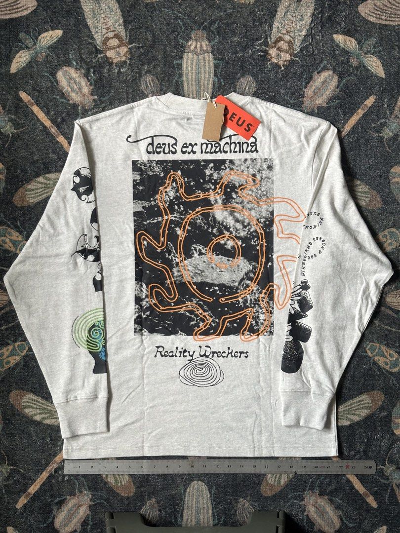 Deus Ex Machina Migration Long Sleeve Tee Light Grey (Category: Tshirts & Polo Shirts ) located in Pasig City. Submitted by scolioolio (Listing ID 1465407093, Image 3). Description: - Brand: Deus Ex Machina - Style: Long sleeve t-shirt - Color: Light grey - Condition: Brand new with original tags attached - Design: Graphic prints on chest, back, and both sleeves (river, butterfly, wasp artwork, and 'Reality Wreckers' text) - Details: Classic crew