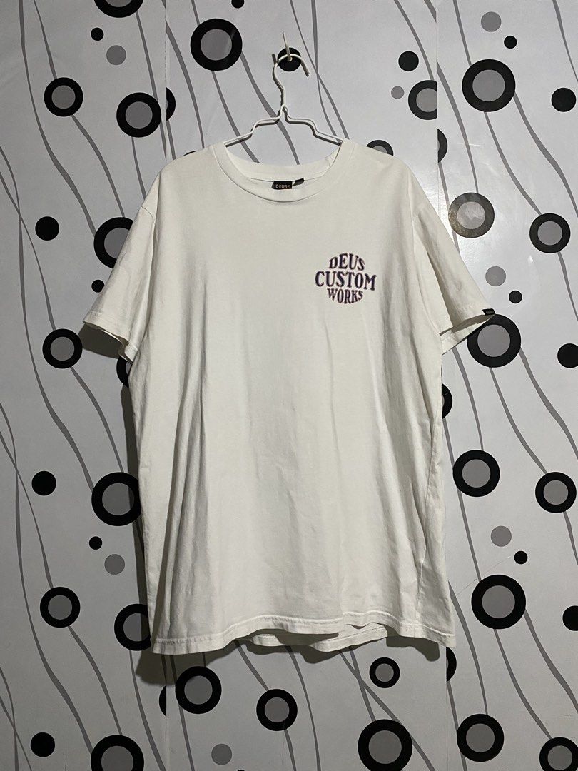Deus Ex Machina Works Tee (Category: Tshirts & Polo Shirts ) located in Cebu City. Submitted by patspickph (Listing ID 1465424281, Image 2). Description: This is a white Deus Ex Machina Works Tee with a retro graphic on the back and also a print Logo on the Front . Size XL on tag Fits L aswell dimensions W22.5 L30.5 Excellent Condition.