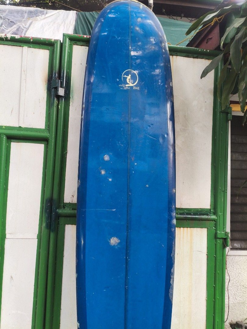 Dewey Weber Longboard Surfboard Blue (Category: Water Sports) located in Manila. Submitted by tonio124 (Listing ID 1465453001, Image 3). Description: - Brand/Model: Dewey Weber classic longboard in deep blue - Design: Features the iconic 'stay close to the soul' logo near the center stringer - Condition: Shows minor dings, pressure bumps, and wax buildup from regular use - Performance: Perfect for smooth wave cruising Board Bag Included - Status: