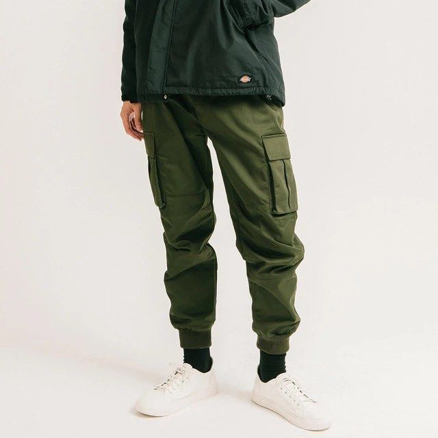 Dickies Olive Green Cargo Jogger Pants (Category: Joggers) located in Badiangan. Submitted by iralorana.thrift (Listing ID 1465430007, Image 1). Description: - Brand: Dickies - Color: Olive green - Style: Casual streetwear cargo joggers - Waistband: Adjustable drawstring with signature logo print and inner logo tape lining - Pockets: Multiple utility pockets on the sides - Cuffs: Elastic ankle cuffs with white branding text near the right - Condi