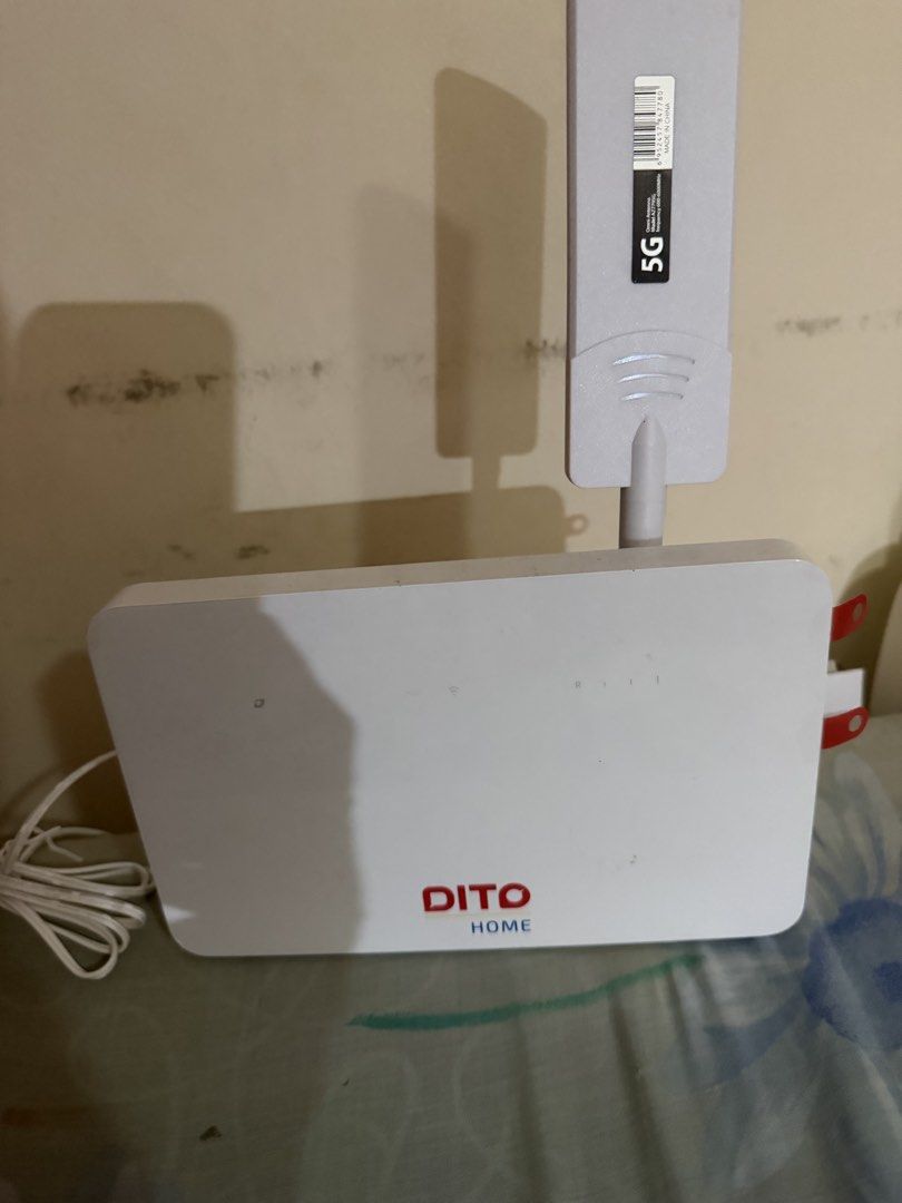 DITO Home 5G Wireless Router with Antenna (Category: Networking) located in Paranaque City. Submitted by mryjwll (Listing ID 1465439178, Image 3). Description: - Model: DITO Home 5G Router in clean white housing - Includes attached 5G omni antenna on top for better signal - Comes complete with power adapter block and long white cable - Features intact red pull tabs on side port covers - 100% clean unit and ready for instant home internet connecti