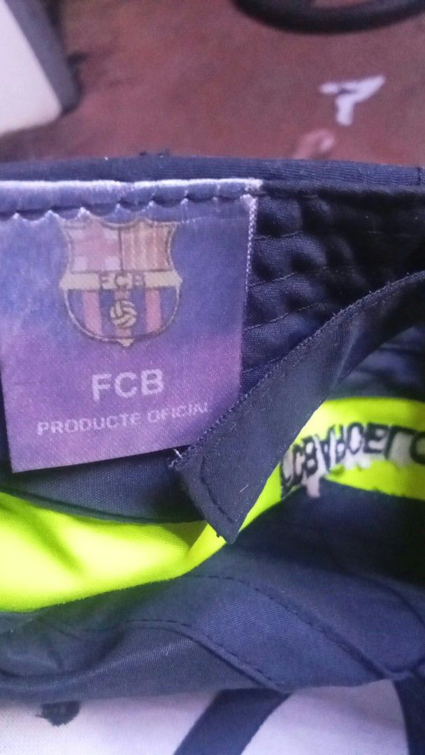 FC Barcelona Official Merchandise Baseball Cap (Category: Caps & Hats) located in Manila. Submitted by josephlim13 (Listing ID 1465428503, Image 3). Description: - Official FC Barcelona merchandise ('Producte Oficial' tag) - Dark grey colorway with striking neon yellow trim - Embroidered club crest on the front and '1899' detail on the brim - 'FC Barcelona' text printed across the adjustable back strap - Clean fabric showing only normal signs of 