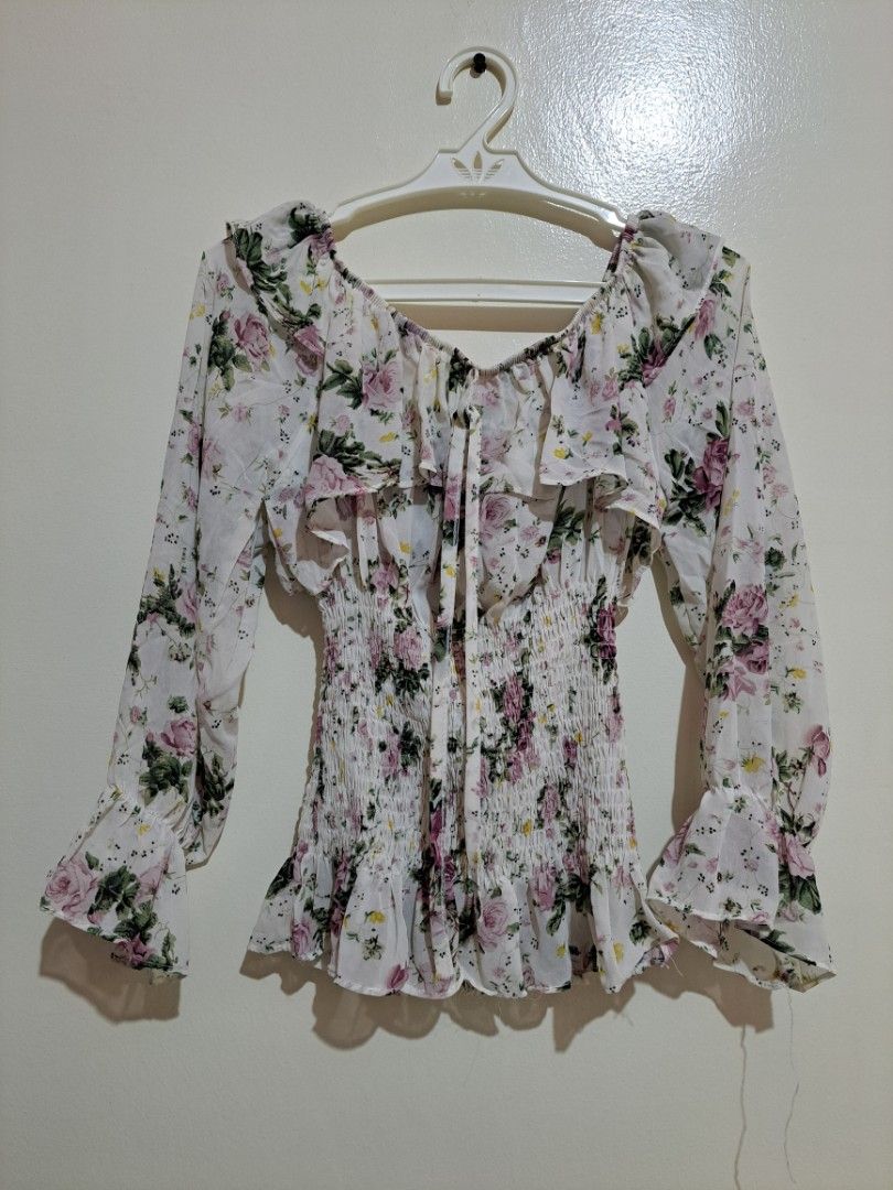 Floral Off-shoulder Long Sleeve Ruffle Blouse (Category: Longsleeves) located in Manila. Submitted by yselles__ (Listing ID 1465388721, Image 1). Description: - Color/Print: White with all-over pink and green floral print - Fit: Stretchy smocked bodice for a snug, flattering fit - Design: Square neckline with front tie detail and ruffle trim on neckline and cuffs - Fabric: Lightweight and breathable, perfect for warm weather or layering - Conditi
