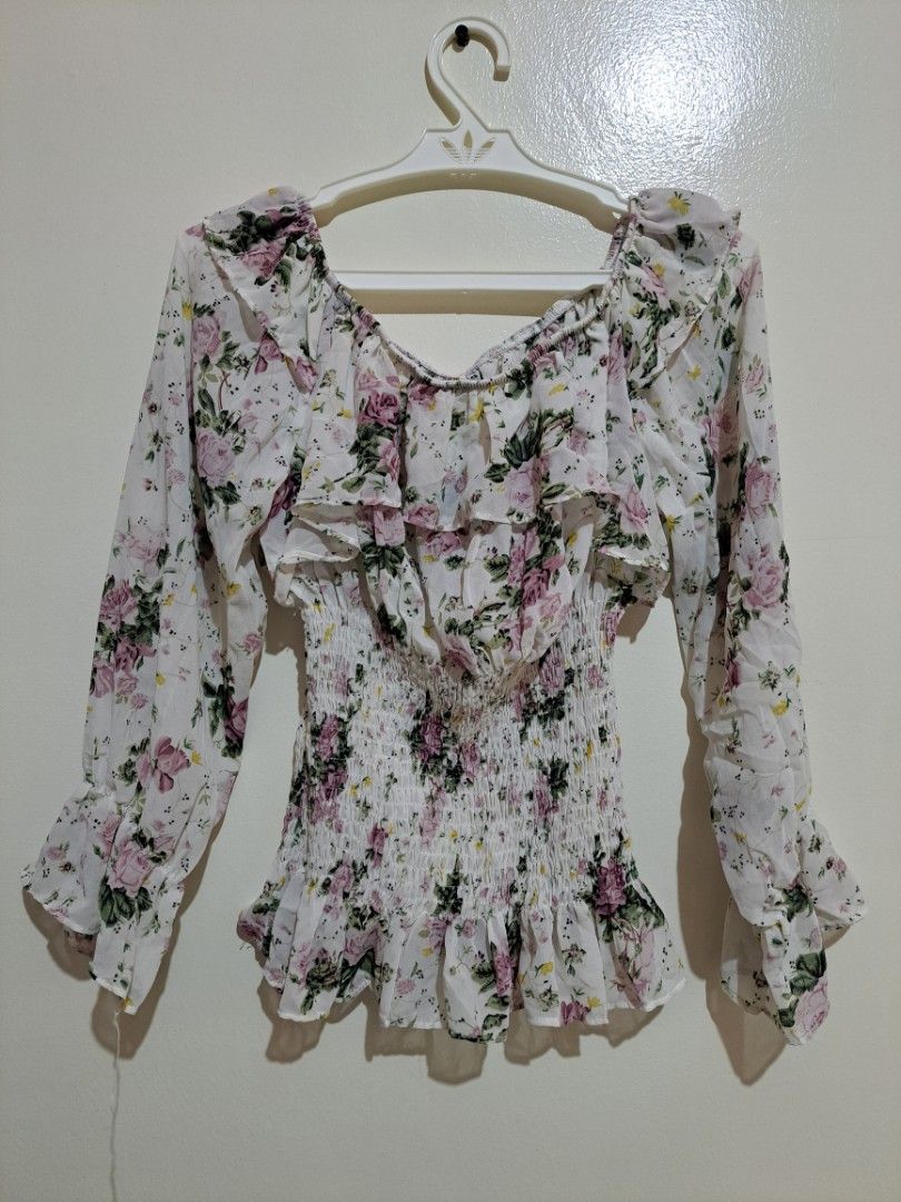 Floral Off-shoulder Long Sleeve Ruffle Blouse (Category: Longsleeves) located in Manila. Submitted by yselles__ (Listing ID 1465388721, Image 2). Description: - Color/Print: White with all-over pink and green floral print - Fit: Stretchy smocked bodice for a snug, flattering fit - Design: Square neckline with front tie detail and ruffle trim on neckline and cuffs - Fabric: Lightweight and breathable, perfect for warm weather or layering - Conditi