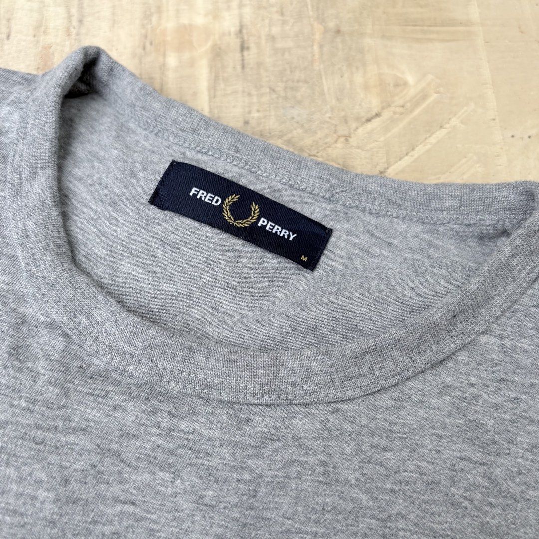 Fred Perry grey t-shirt size M (Category: Tshirts & Polo Shirts ) located in Tagum. Submitted by johntams_ (Listing ID 1465481145, Image 2). Description: - Brand: Fred Perry - Color: Heather Grey - Size: Medium - Fit: Classic fit, short sleeves - Material: Soft cotton blend - Details: Embroidered white laurel wreath logo near hem, black brand label inside collar - Condition/Style: Clean basic tee, perfect for daily wear.