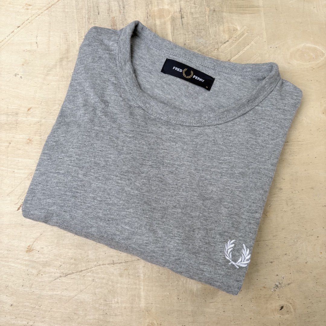 Fred Perry grey t-shirt size M (Category: Tshirts & Polo Shirts ) located in Tagum. Submitted by johntams_ (Listing ID 1465481145, Image 1). Description: - Brand: Fred Perry - Color: Heather Grey - Size: Medium - Fit: Classic fit, short sleeves - Material: Soft cotton blend - Details: Embroidered white laurel wreath logo near hem, black brand label inside collar - Condition/Style: Clean basic tee, perfect for daily wear.