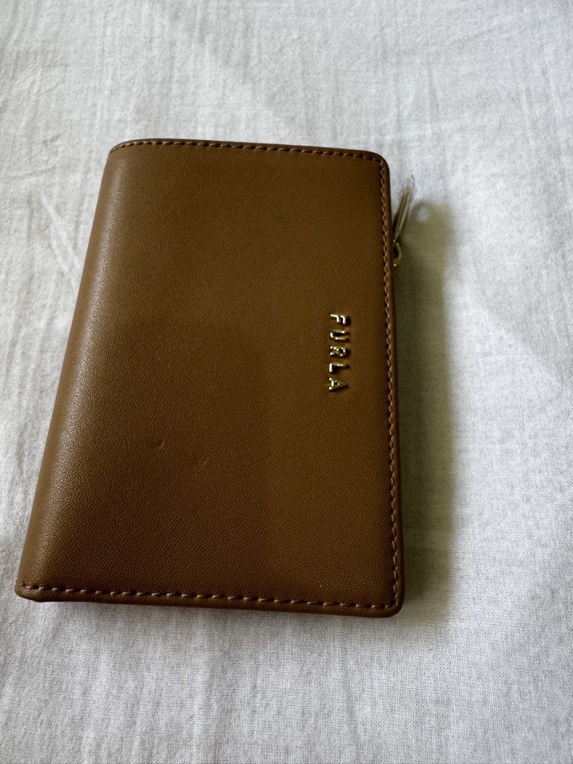 Furla Brown Leather Bifold Wallet (Category: Wallets & Card holders) located in Manila. Submitted by cmm2025 (Listing ID 1465402403, Image 1). Description: - Brand: Furla - Material: Brown leather with gold-toned metal logo lettering - Closure: Secure snap button closure - Storage: Multiple card slots and compartments - Coin Pocket: Convenient side zipper pocket for coins or small items - Design: Compact size that fits easily into any bag - Condi