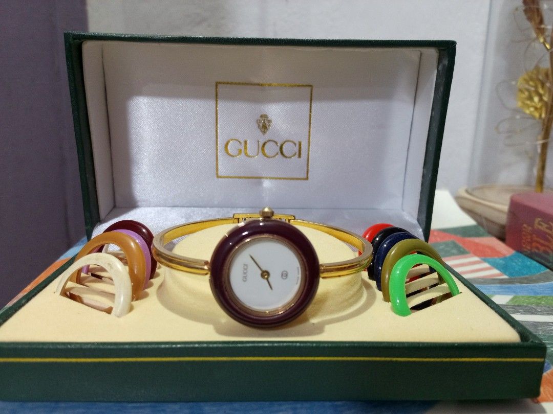 Gucci Interchangeable Bezel Bangle Watch with Box (Category: Women's Watches) located in Malolos. Submitted by lizarondoe59660 (Listing ID 1465484760, Image 2). Description: - Authentic vintage Gucci bangle watch from the 1980s or 1990s - Elegant gold-tone finish with a clean, scratch-free white dial and crystal - Comes with multiple interchangeable colored bezel rings to match any outfit - Includes the original green presentation box for safe st