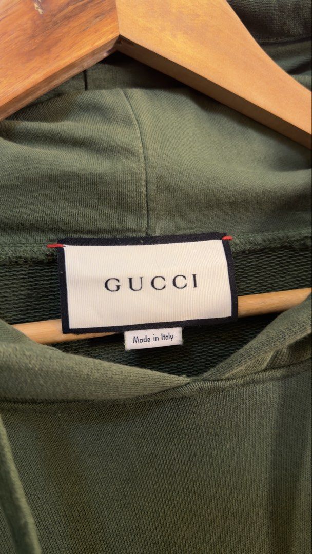 Gucci Interlocking G Olive Green Hoodie Size M (Category: Coats, Jackets and Outerwear) located in Paranaque City. Submitted by preluxeshop_ph (Listing ID 1465555586, Image 3). Description: Gucci Interlocking G Olive Green Hoodie Size M - Size: Medium (Made in Italy) - Cream and black jacquard stripe tape with interlocking G logo on both sleeves - Premium cotton loopback fleece fabric - Drawstring hood with ribbed cuffs and hem - Clean piece with