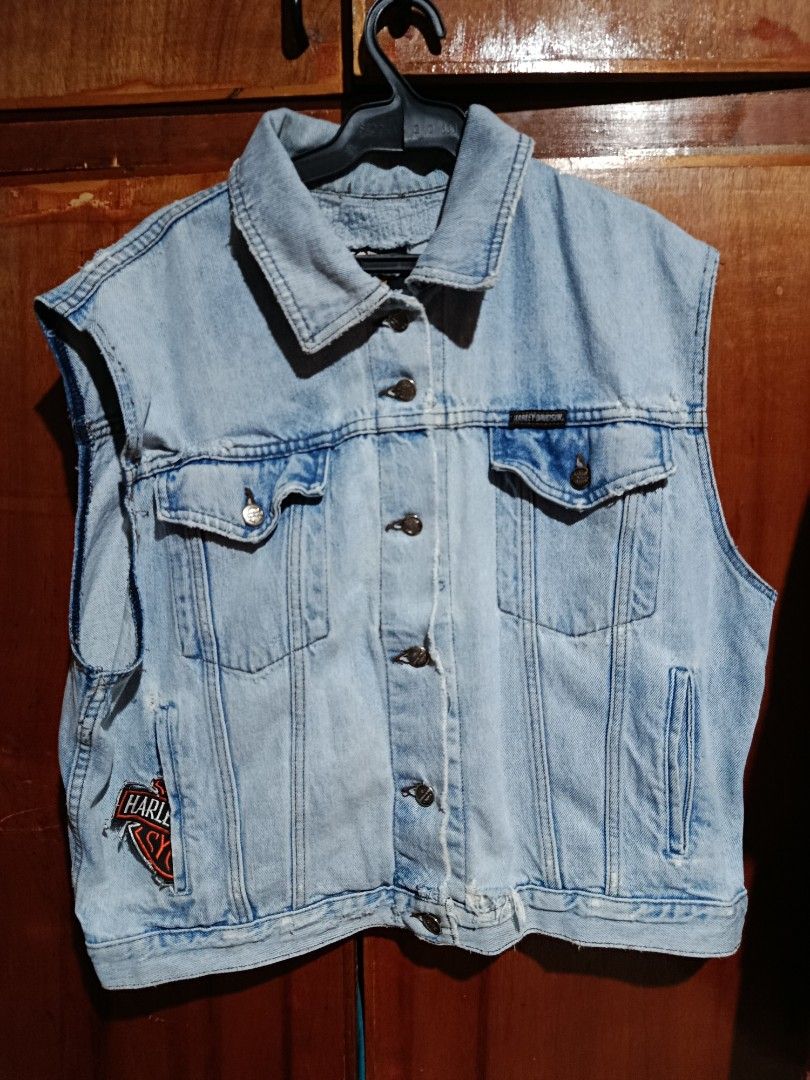 Harley-Davidson Light Wash Denim Vest (Category: Vests) located in Baguio. Submitted by dlv89288 (Listing ID 1465491573, Image 1). Description: - Brand: Harley-Davidson - Style: Classic biker denim vest, light wash with distressed edges - Closure: Button-down front with branded metal buttons - Pockets: Dual chest pockets with button flaps plus side pockets - Details: Embroidered Harley-Davidson patch on lower front and black brand tag above right