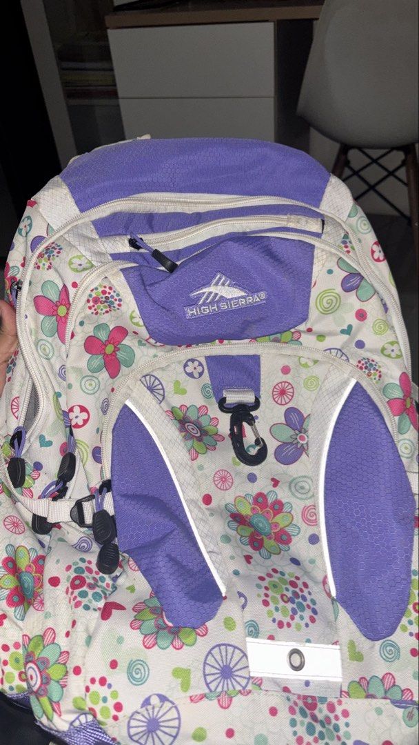 High Sierra Hiking Purple Backpack (Category: Backpacks) located in Manila. Submitted by cheetosjalapeno.f6b498 (Listing ID 1465534525, Image 2). Description: High Sierra backpack with a fun floral pattern against a white and purple design. Includes padded shoulder straps featuring their suspension system for extra comfort. Multiple zippered compartments and front clip attached. Built for school, travel, or everyday use. Shows some light wear alo