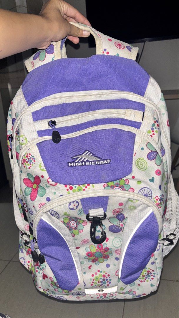 High Sierra Hiking Purple Backpack (Category: Backpacks) located in Manila. Submitted by cheetosjalapeno.f6b498 (Listing ID 1465534525, Image 1). Description: High Sierra backpack with a fun floral pattern against a white and purple design. Includes padded shoulder straps featuring their suspension system for extra comfort. Multiple zippered compartments and front clip attached. Built for school, travel, or everyday use. Shows some light wear alo