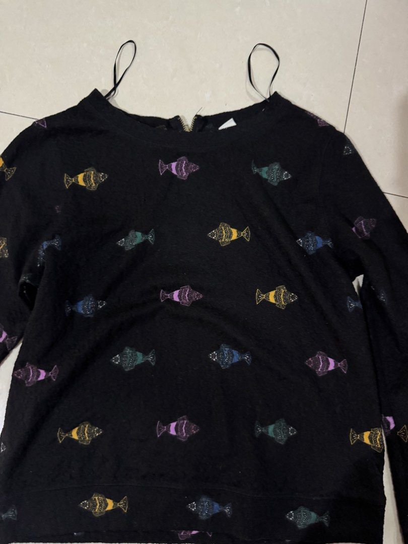 H&M Black Fish Print Sweatshirt (Category: Longsleeves) located in Quezon City. Submitted by sweetlyluxe (Listing ID 1465487100, Image 2). Description: - Brand: H&M - Size: XS but fits S - Color: Black with colorful fish prints (yellow, purple, blue, green) - Material: Soft textured fabric - Features: Gold zipper detail at the back neckline, shoulder strap loops - Style: Simple pull-on long sleeve sweater for winter.