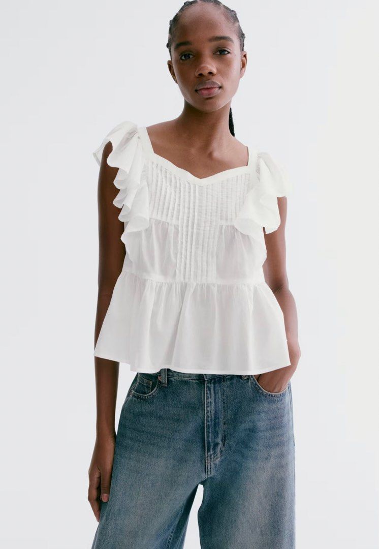H&M Divided White Ruffle Pleated Blouse Top (Category: Blouses) located in La Paz. Submitted by cldn.co (Listing ID 1465395969, Image 2). Description: - Brand: H&M Divided - Color: White - Material: Lightweight cotton - Design details: Dramatic ruffled cap sleeves, pintuck pleating on the front, and a tiered peplum hem - Neckline: Square neckline - Condition: Clean and ready to wear - Styling tip: Perfect to pair with high-waisted denim jeans or 