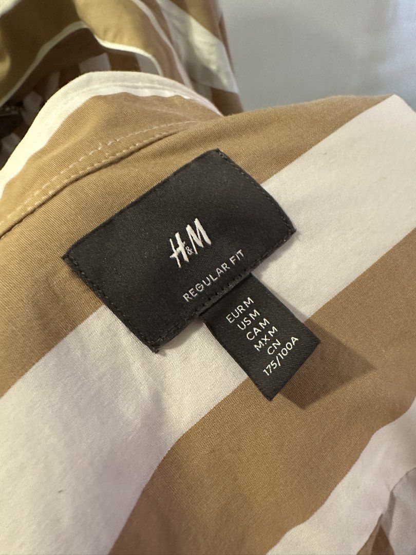 H&M Striped Regular Fit Button-Down Shirt Size M (Category: Tshirts & Polo Shirts ) located in Manila. Submitted by chris9837 (Listing ID 1465414121, Image 2). Description: - Brand: H&M - Style: Button-down shirt with classic collar and front closure - Fit: Regular fit - Pattern: Brown and white vertical stripes - Size: M (corresponds to 175/100A) - Condition: Clean fabric, tags intact Location: Parañaque. .