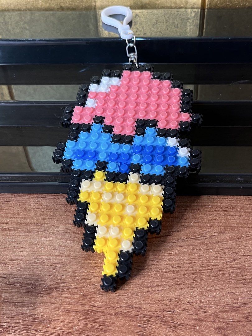 Ice cream cone pixel block keychain (Category: Character Goods) located in Gapan. Submitted by lunashop14 (Listing ID 1465565025, Image 2). Description: - Handmade ice cream cone keychain made from mini pixel blocks - Features pink and blue scoops with black outlines and a yellow waffle cone - Equipped with a white plastic clasp ring for easy hanging - Fun and colorful accessory perfect for bags, keys, or lanyards - Lightweight, unique, and great