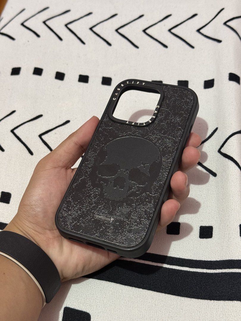 (iPhone 16 Pro) CASETiFY Impact Case DEFINITELY DISTRESSED (Category: Cases & Sleeves) located in Baguio. Submitted by nathan2123 (Listing ID 1465490642, Image 2). Description: Compatibility: iPhone 16 PRO Material: Polycarbonate BACK, Polyurethane/TPU FRAME✅ Design: All Black SKULL✅ Magsafe Compatible: Yes ✅ Scratches: Well (to) Light❗️ Dents: Slight dent on the Camera Button Cutout and USB-C Cutout (long-term used)❗️ Flaws: Has discoloration on