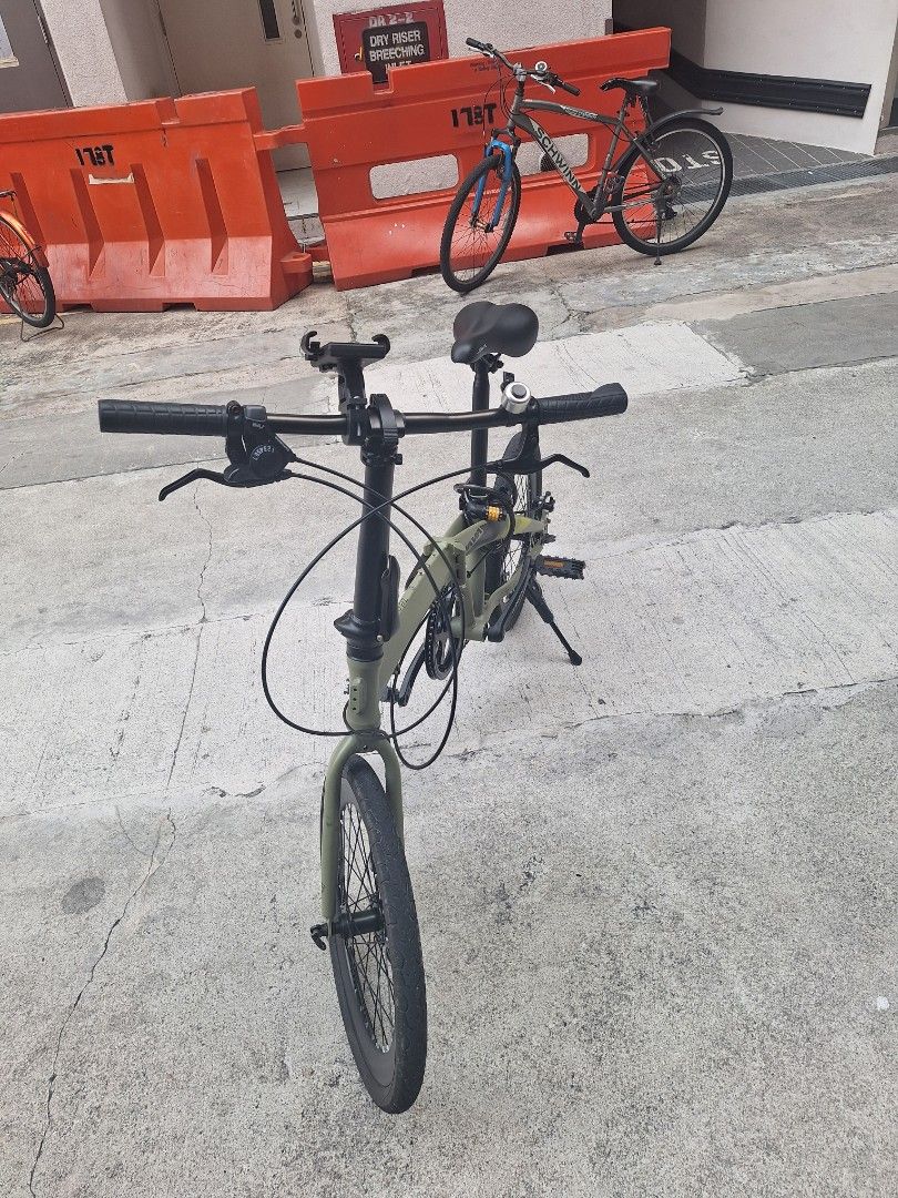 JAVA Green Folding Bicycle (Category: Bicycles) located in Singapore. Submitted by mdmonirujj67123 (Listing ID 1465439760, Image 4). Description: - Brand: JAVA - Color: Green with black saddle, handlebars, and wheels - Brakes: Reliable disc brakes - Portability: Lightweight and folds smoothly for storage or public transport - Included Accessories: Mounted kickstand, phone holder, bell, and coiled combination lock - Ideal For: Urban commuting and 