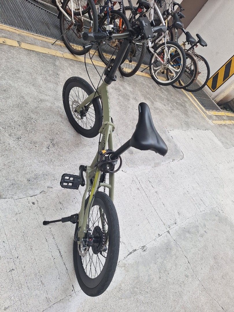 JAVA Green Folding Bicycle (Category: Bicycles) located in Singapore. Submitted by mdmonirujj67123 (Listing ID 1465439760, Image 3). Description: - Brand: JAVA - Color: Green with black saddle, handlebars, and wheels - Brakes: Reliable disc brakes - Portability: Lightweight and folds smoothly for storage or public transport - Included Accessories: Mounted kickstand, phone holder, bell, and coiled combination lock - Ideal For: Urban commuting and 