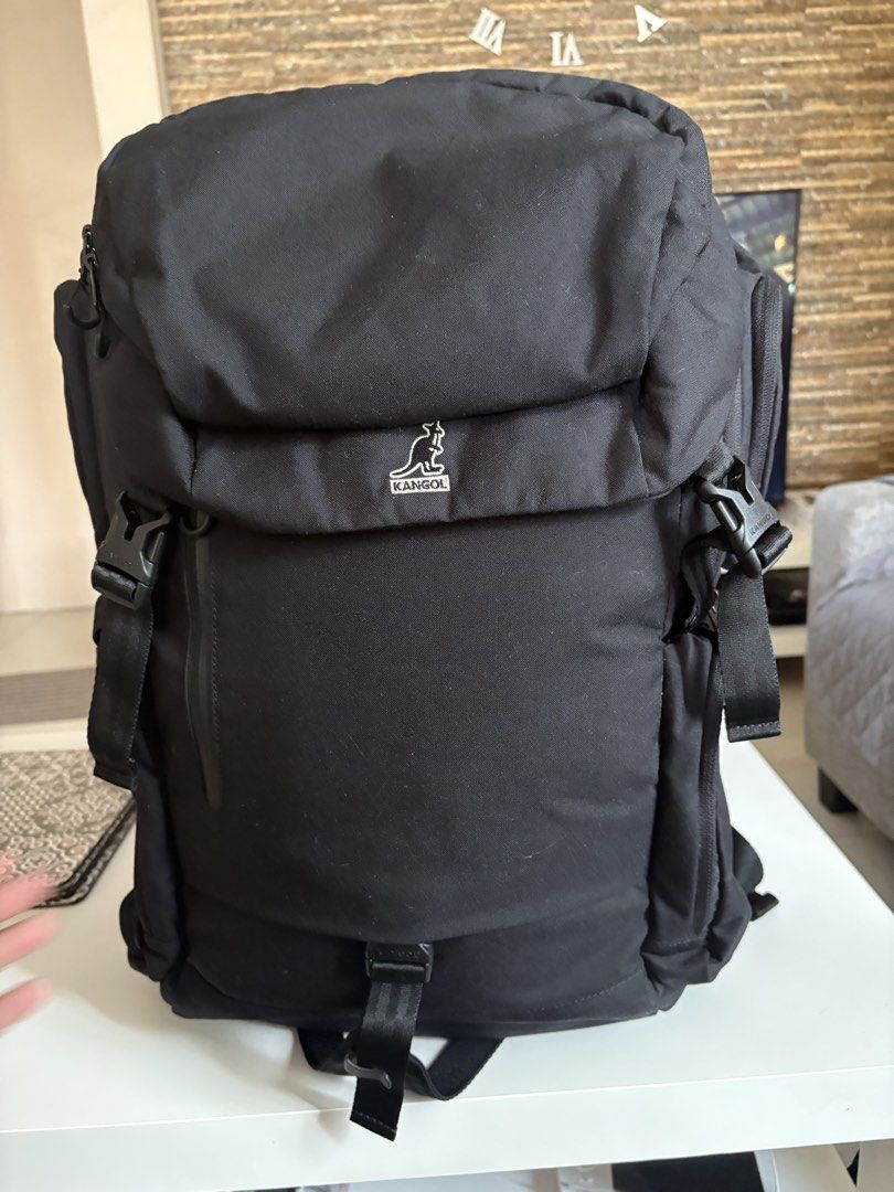 Kangol Black Backpack with Multiple Compartments (Category: Backpacks) located in Manila. Submitted by kakiboyo (Listing ID 1465392869, Image 1). Description: Black Kangol backpack with lots of storage. Front logo patch and side zip pockets. Padded shoulder straps with buckle details. Inside has a laptop sleeve, mesh zipper pocket, and utility slots with name tags. Clean grey interior lining..