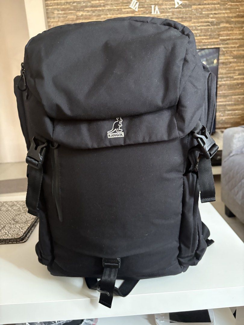 Kangol Black Backpack with Multiple Compartments (Category: Backpacks) located in Manila. Submitted by kakiboyo (Listing ID 1465392869, Image 2). Description: Black Kangol backpack with lots of storage. Front logo patch and side zip pockets. Padded shoulder straps with buckle details. Inside has a laptop sleeve, mesh zipper pocket, and utility slots with name tags. Clean grey interior lining..
