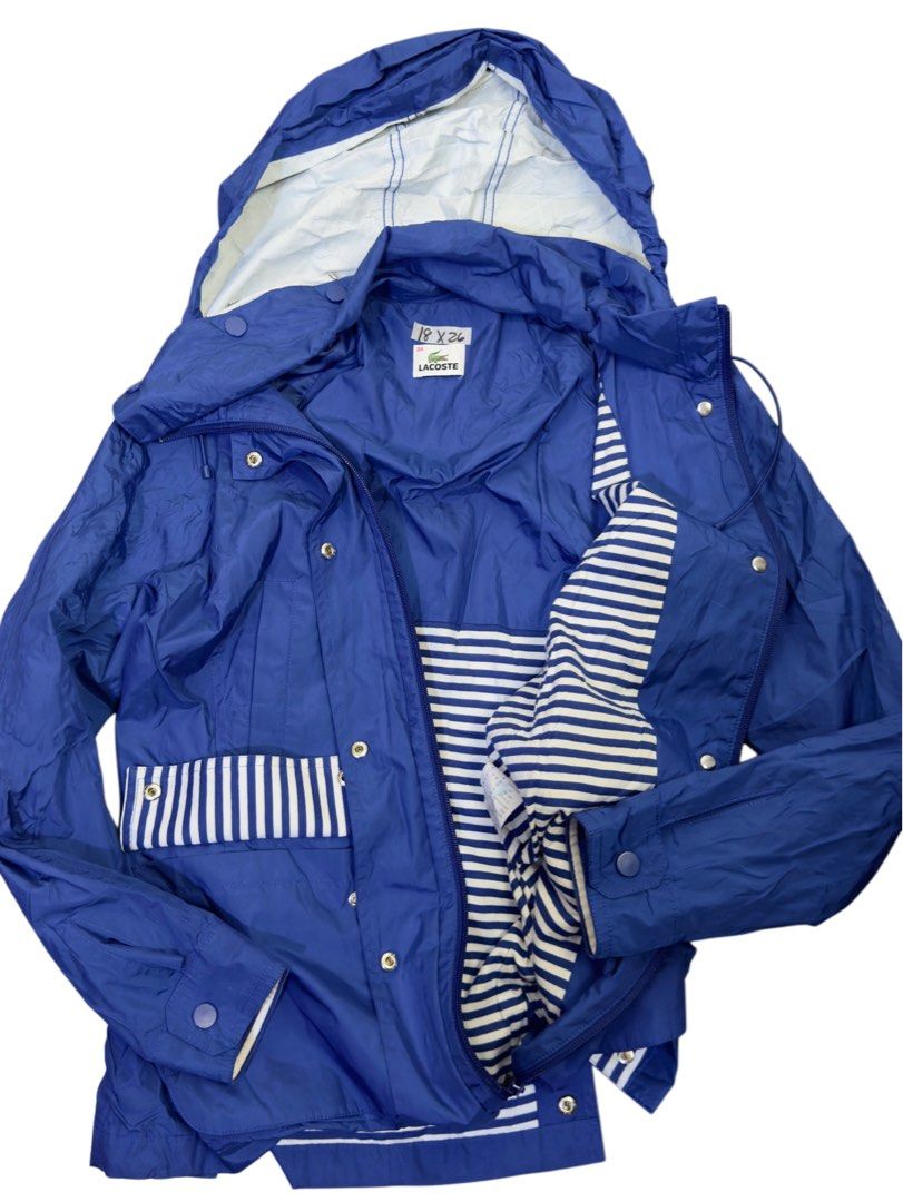 Lacoste Blue Hooded Windbreaker Jacket Size 34 (Category: Coats, Jackets and Outerwear) located in Caloocan City. Submitted by mzcollection_349 (Listing ID 1465403333, Image 2). Description: - Brand: Lacoste - Color: Royal blue with blue & white striped lining accents - Size: 34 - Design: Full zip front with snap-button storm flap, high neck collar with drawstrings - Details: Classic tonal embroidered crocodile logo on the chest, functional pocke