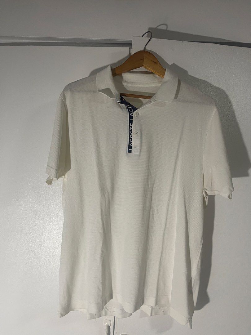 Lacoste White Polo Shirt with Contrast Placket (Category: Tshirts & Polo Shirts ) located in Manila. Submitted by kyllyzzle (Listing ID 1465562403, Image 1). Description: White short sleeve polo shirt from Lacoste. Textured pique fabric throughout. Navy blue placket interior featuring bold white LACOSTE lettering down the button closure. Two white branded buttons at the neck. Classic collar style. Clean back with no graphics. Simple casual piece 