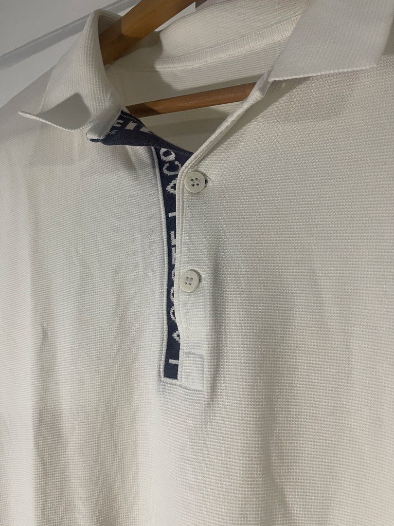 Lacoste White Polo Shirt with Contrast Placket (Category: Tshirts & Polo Shirts ) located in Manila. Submitted by kyllyzzle (Listing ID 1465562403, Image 2). Description: White short sleeve polo shirt from Lacoste. Textured pique fabric throughout. Navy blue placket interior featuring bold white LACOSTE lettering down the button closure. Two white branded buttons at the neck. Classic collar style. Clean back with no graphics. Simple casual piece 