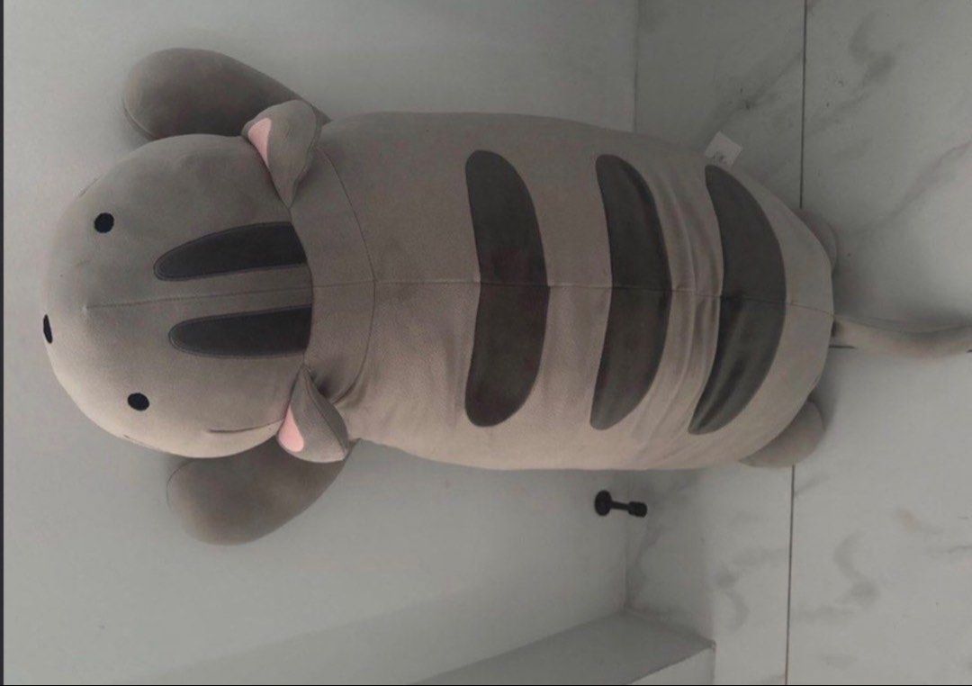 Large grey striped cat plush body pillow (Category: Bedding & Towels) located in Manila. Submitted by decluterthings888 (Listing ID 1465397652, Image 3). Description: - Super soft giant cat pillow in grey with dark grey stripes - Features cute pink inner ears and black embroidered eyes - Extra-long body, perfect for hugging while sleeping or lounging - Clean fabric with zero stains or damage - Smoke-free and well-maintained condition.