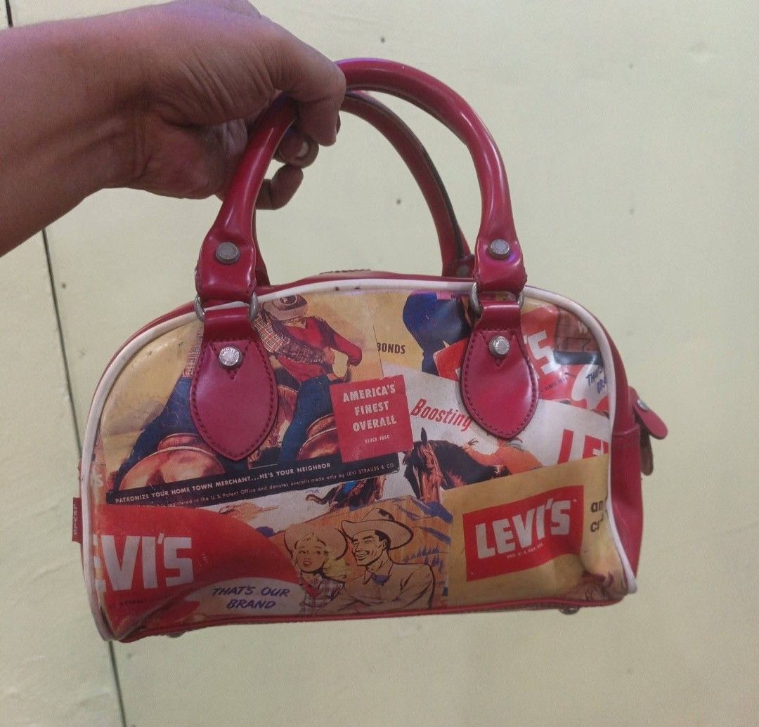 Levi's Vintage Print Handbag Red (Category: Tote Bags) located in San Carlos City. Submitted by dhong_abay_thrift (Listing ID 1465384571, Image 1). Description: - Brand: Levi Strauss Korea (Model: 35617-BG59) - Design: Eye-catching vintage cowboy & advertisement graphic print in red - Material: 100% PVC (durable and easy to wipe clean) - Straps: Sturdy double top handles with red trim - Interior: Clean lining with original product tag intact - Co
