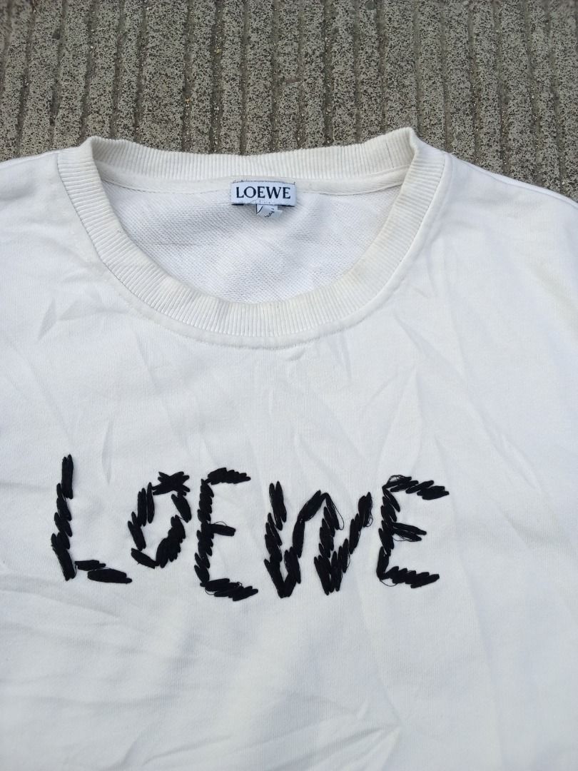 Loewe White Embroidered Logo Sweatshirt (Category: Luxury Apparel) located in Caloocan City. Submitted by mysticdog-6a6b (Listing ID 1465447930, Image 2). Description: - Brand: Loewe - Color: White with embroidered black lettering - Size: XL but fit to large - Material: 100% Cotton (Made in Portugal) - Style: Crewneck with ribbed cuffs and hem - Condition: Good, with minor yellowing near the collar from previous wear - Authentic luxury piece read