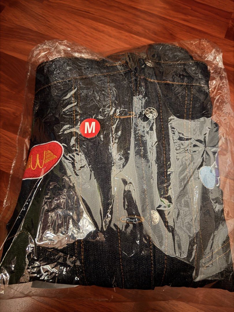 McDonald's Denim Jacket Size M (Category: Coats, Jackets and Outerwear) located in Manila. Submitted by adc.c (Listing ID 1465455782, Image 1). Description: - Brand: McDonald's Collab Dark Denim Jacket - Condition: Brand new, still sealed in original plastic packaging - Size: Medium (23" chest, 24.5" length) - Details: Decorated with iconic McDonald's character and food patches on front and sleeves - Accents: Stylish orange contrast stitching and