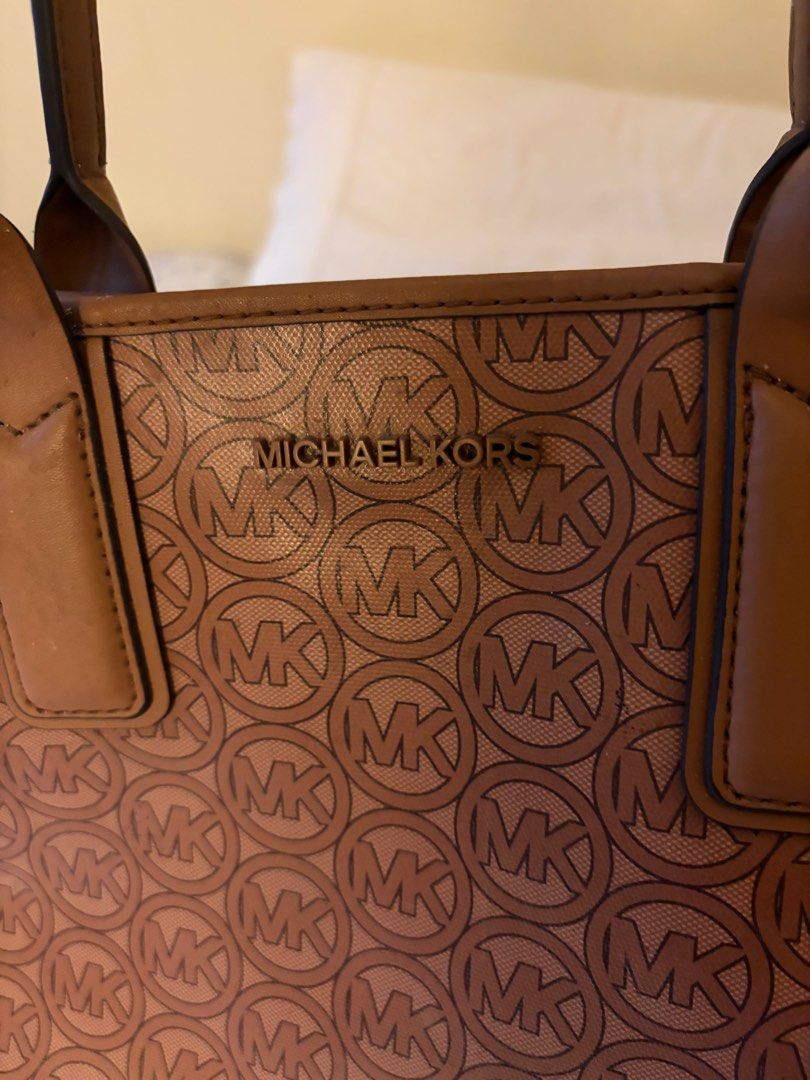 Michael Kors Brown MK Monogram Tote Bag (Category: Luxury Bags & Wallets) located in Cainta. Submitted by kayden1912 (Listing ID 1465456171, Image 3). Description: - Authentic Michael Kors brown monogram tote bag - Structured silhouette with sturdy, comfortable shoulder straps - Elegant gold-tone hardware with front logo lettering - Spacious interior ideal for daily work essentials or running errands - Condition: Excellent / Well-maintained - Mod