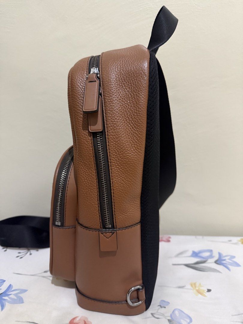 Michael Kors Cooper Pebbled Leather Sling Bag (Category: Backpacks) located in Quezon City. Submitted by zeepeebee (Listing ID 1465507323, Image 2). Description: - Brand: Michael Kors - Material: Textured brown leather with silver hardware - Design: Front pocket with logo lettering, secure zip closures - Comfort: Adjustable black webbing strap & breathable mesh back panel - Interior: Clean lining with handy slip pockets - Condition: Excellent / W