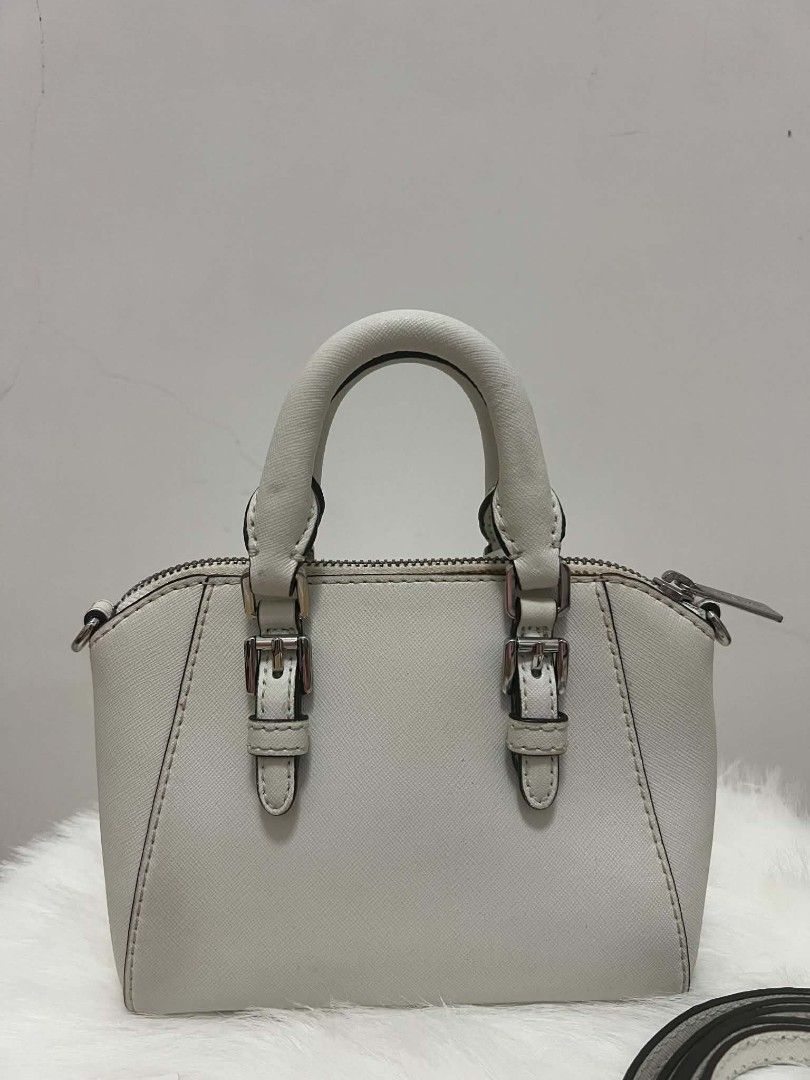 Michael Kors Mini Ciara Crossbody Bag (Category: Cross-body Bags) located in Paoay. Submitted by rvf1230 (Listing ID 1465423908, Image 3). Description: - Authentic Michael Kors dome satchel in crisp white Saffiano leather - Silver-tone hardware with front MK lettering and logo charm hangtag - Dual top handles and adjustable, removable crossbody strap - Top zip closure with clean MK signature interior lining - Includes interior slip pockets and ca