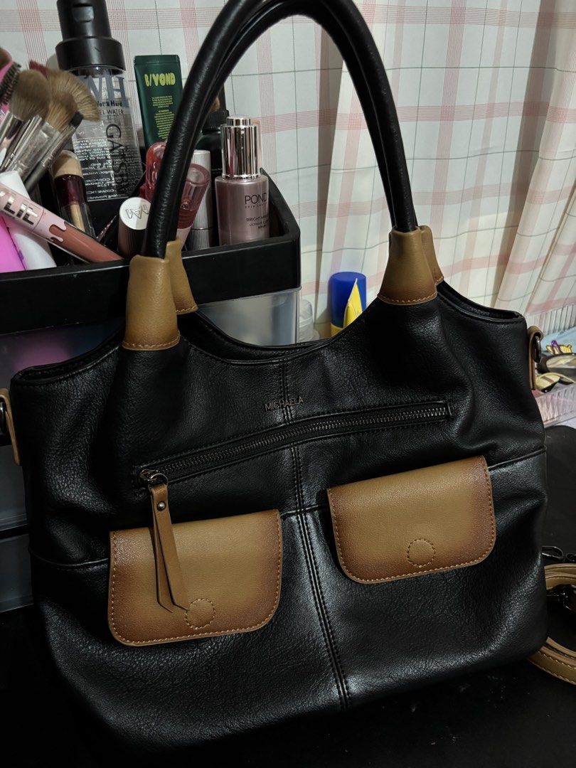 MICHAELA Black and Brown Two-Tone Shoulder Bag (Category: Shoulder Bags) located in Manila. Submitted by mia0825.07 (Listing ID 1465502651, Image 1). Description: - Brand: MICHAELA - Color: Black with stylish brown pocket flaps and handle accents - Closure: Secure top zipper - Pockets: 1 front zip pocket, 2 front flap pockets, and a clean spacious interior - Straps: Sturdy black shoulder straps - Use: Ideal size for daily use, work, or school.