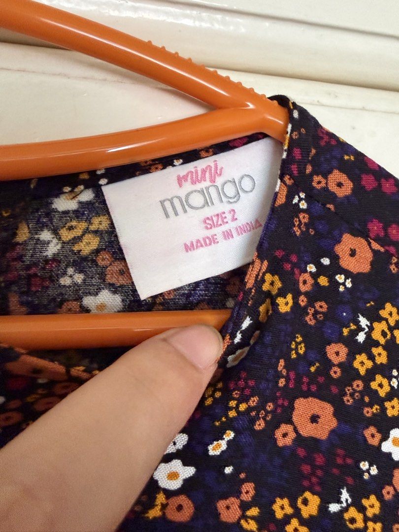 Mini Mango Floral Dress (Category: Babies & Kids Fashion) located in Paranaque City. Submitted by mayan_q (Listing ID 1465450845, Image 2). Description: - Brand: Mango - Size: 2 (Made in India) - Design: Black with vibrant orange, white, and yellow floral print - Features: 3/4 sleeves, gathered waist, cute tiered skirt, and 3 wooden buttons at the back neckline - Material: Lightweight and comfortable fabric - Condition: Excellent / Brand new-like
