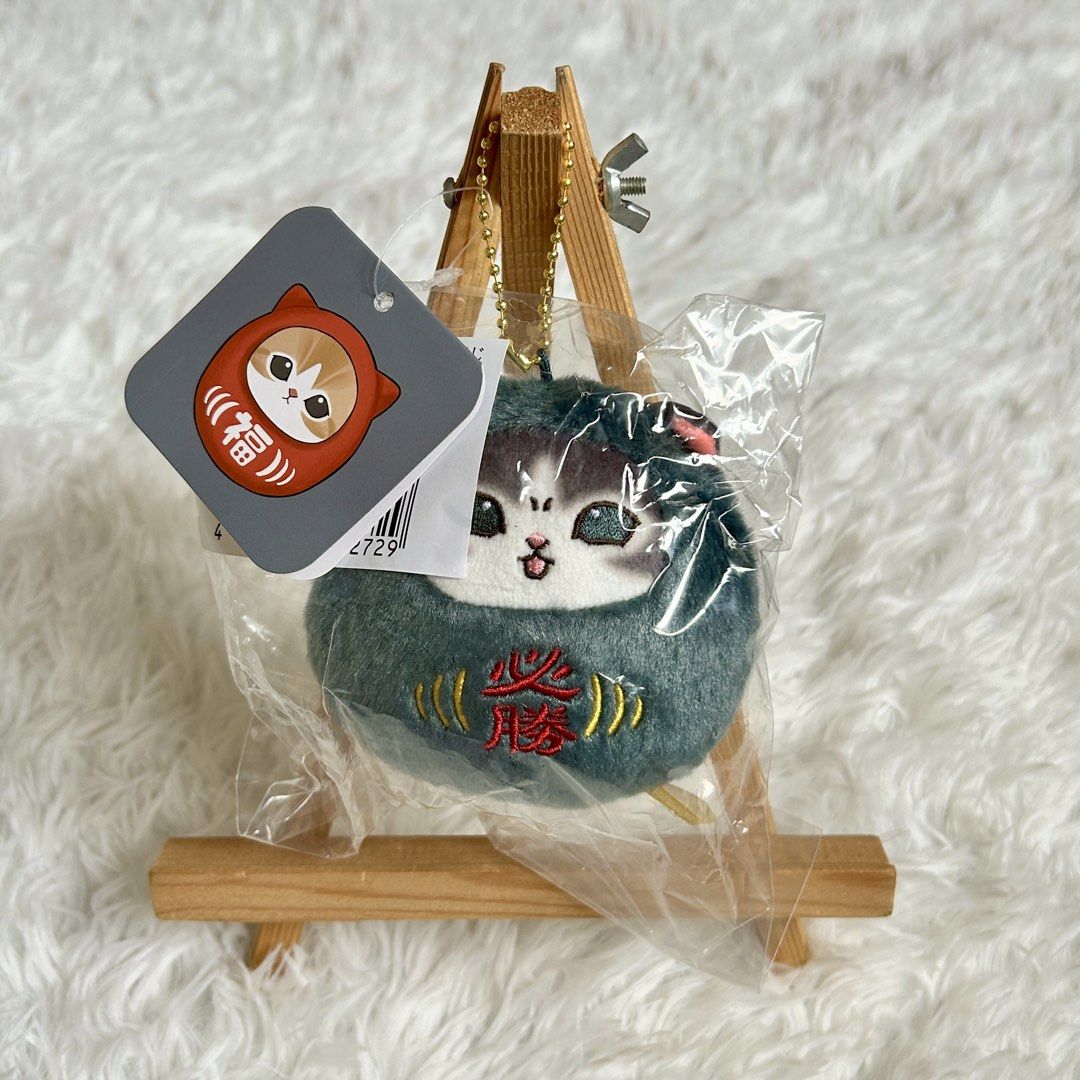 Mofusand Daruma Plush Keychain Lucky Charm (Category: Plushies & Soft Toys) located in Manila. Submitted by nekollection_ph (Listing ID 1465416517, Image 1). Description: - Authentic Japanese cat daruma plush keychain - Features cute kanji embroidery and a small, round soft toy design - Equipped with a gold bead chain for easy attachment to bags or keys - Brand new, sealed in original plastic packaging with paper tag intact - Available in 2 color