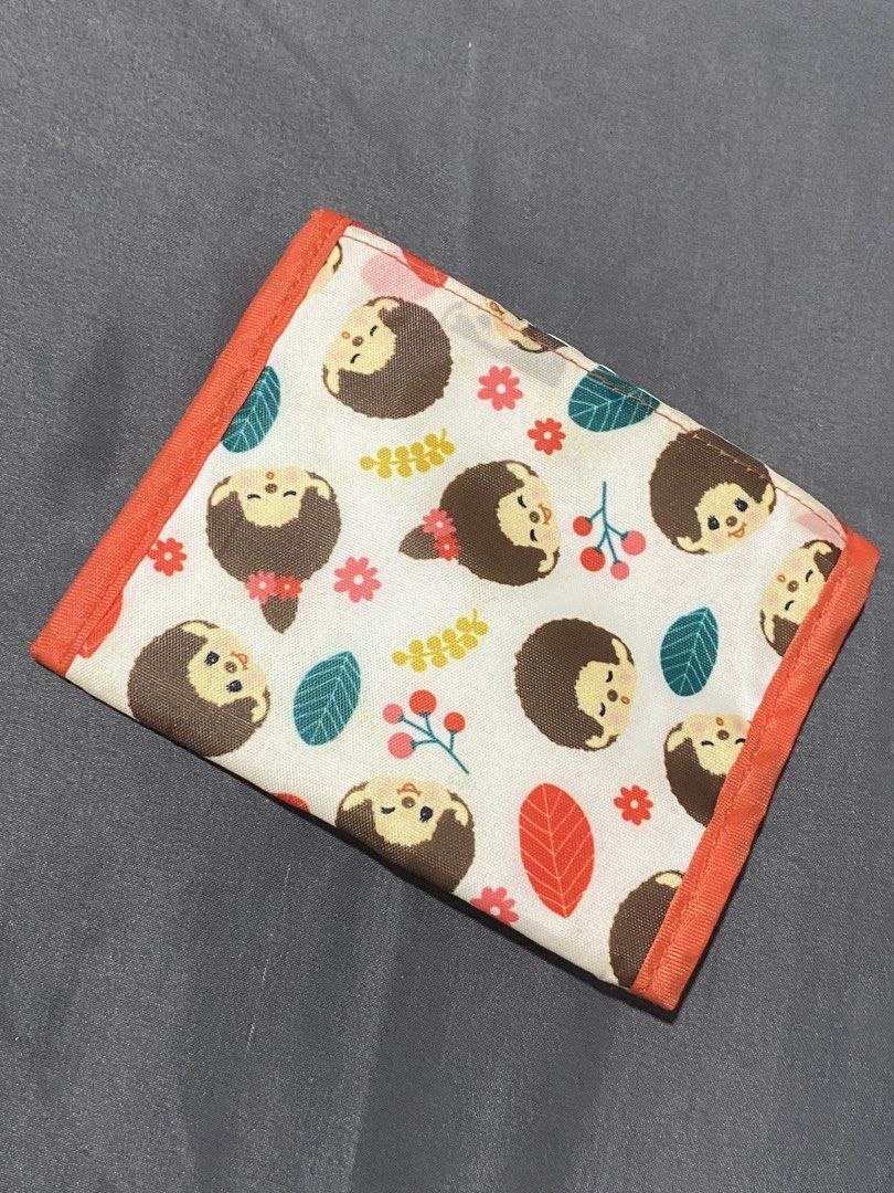 Monchhichi Print Trifold Wallet (Category: Wallets & Card holders) located in Manila. Submitted by faerikhae (Listing ID 1465546886, Image 2). Description: - Authentic Monchhichi trifold wallet - Adorable all-over hedgehog, leaves, and floral pattern with orange trim - Secure front snap button closure - Interior features multiple card slots and a convenient clear ID pocket - Official 2020 Sekiguchi Monchhichi fabric tag - Compact and lightweight,