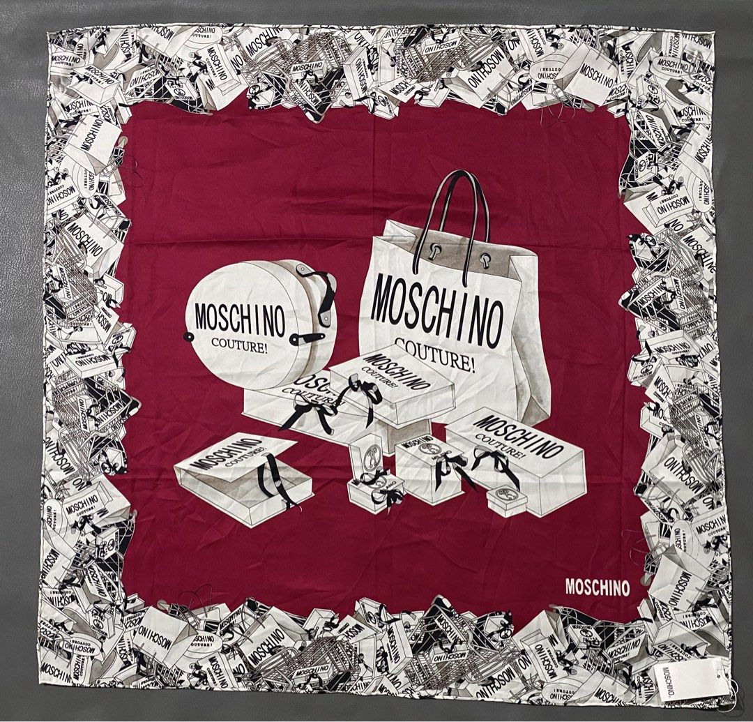 Moschino Couture Silk Scarf (Category: Scarves) located in Pozorrubio. Submitted by izaykite2g (Listing ID 1465524588, Image 1). Description: - Brand: Moschino Couture - 34 x 34.5 inches - Material: 100% Silk (Made in France) - Design: Bold red center with a black and white illustrated shopping bag and box graphic border - Shape: Square - Condition: Brand new with original tags still attached - Perfect luxury gift or stylish accessory.