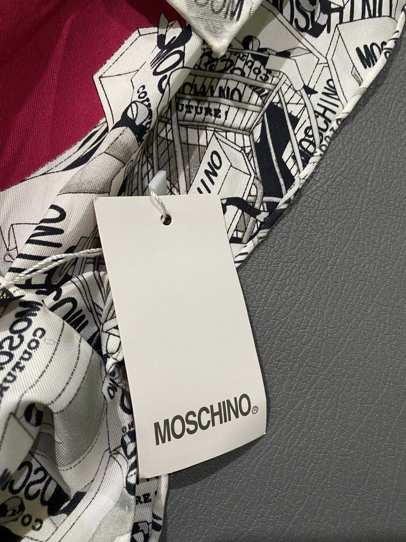Moschino Couture Silk Scarf (Category: Scarves) located in Pozorrubio. Submitted by izaykite2g (Listing ID 1465524588, Image 2). Description: - Brand: Moschino Couture - 34 x 34.5 inches - Material: 100% Silk (Made in France) - Design: Bold red center with a black and white illustrated shopping bag and box graphic border - Shape: Square - Condition: Brand new with original tags still attached - Perfect luxury gift or stylish accessory.